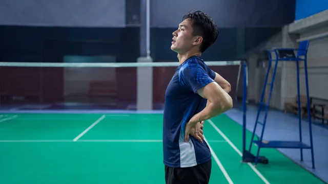 Pemain badminton pemula memegang pinggang setelah bermain pertama kali