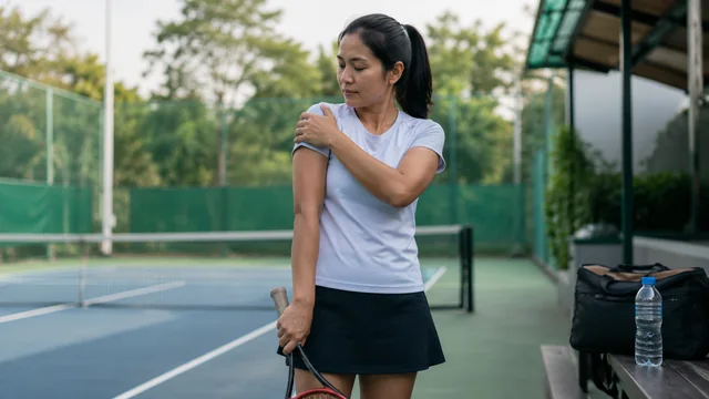 Pemain tenis memegang bahu setelah bermain tenis