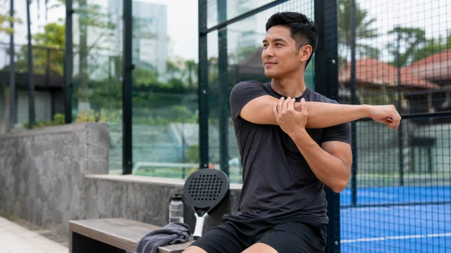 Pemain padel menggerakkan bahu perlahan setelah sesi latihan
