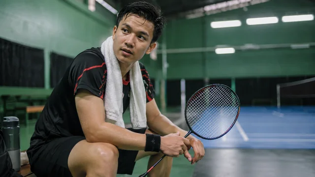 Pemain badminton duduk dengan lutut terlihat setelah bermain