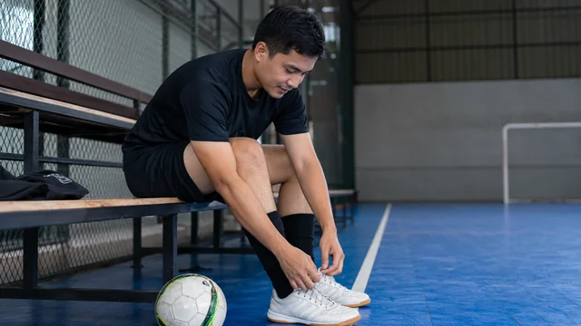 Pemain futsal duduk dengan lutut terlihat setelah bermain