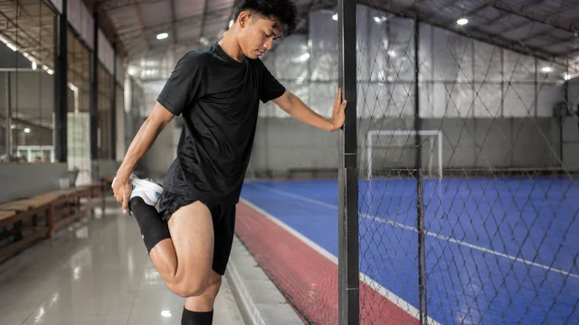Pemain futsal melakukan peregangan paha setelah bermain