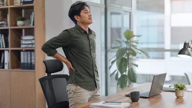 Pekerja berdiri dari kursi untuk meregangkan pinggang belakang