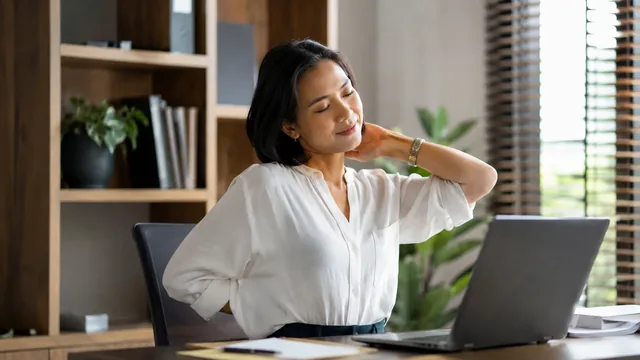 Orang dewasa meregangkan pundak dan leher setelah bekerja di laptop
